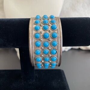 Adjustable 1.65” wide bangle. Featuring small blue stones.